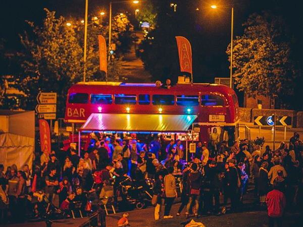 Bus bar lit up at a night-time festival
